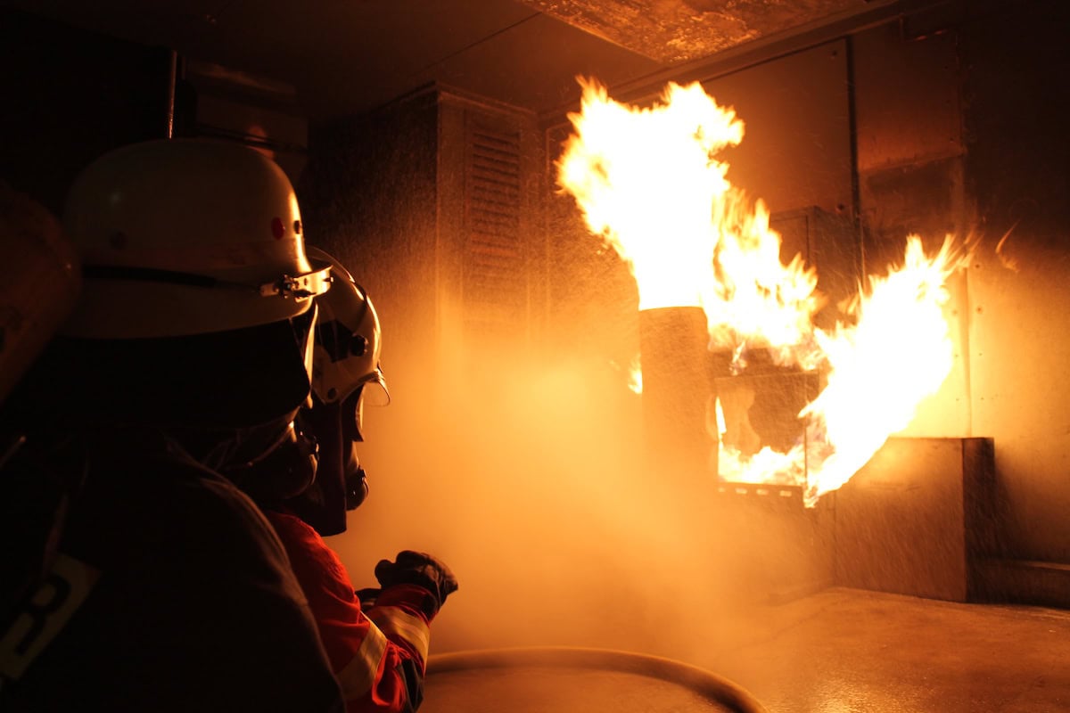 Einsatzkraft mit Atemschutz vor offenem Feuer